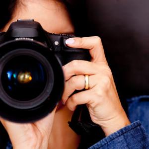 Portrait of a photographer covering her face with the camera